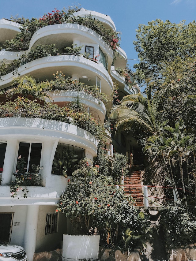 Ein mehrstöckiges Haus mit gestuften Terrassen, die alle mit vielen Pflanzen bedeckt sind
