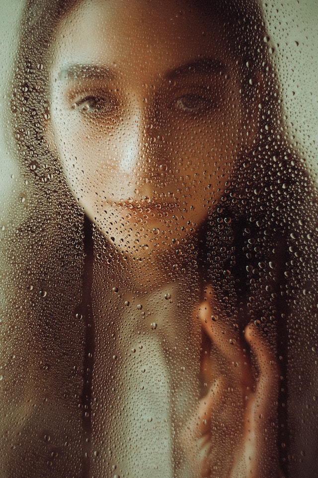 Die Reflexion einer Frau auf einer angelaufenen Siegelscheibe voller Wassertropfen