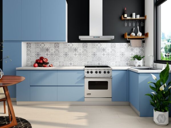 Eine schlichte, hellblaue Küche mit weißer Arbeitsplatte und gemustertem Fliesenspiegel