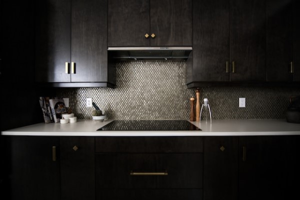 Eine edle dunkle Kücheneinrichtung in Braun- und Schwarztönen mit einer weißen Arbeitsplatte.