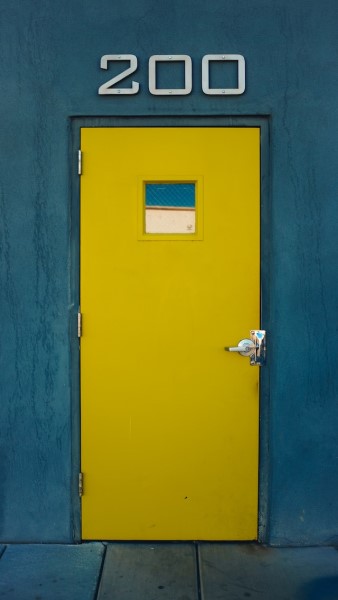 Eine gelbe Metalltür in einer dunkelblauen Wand.