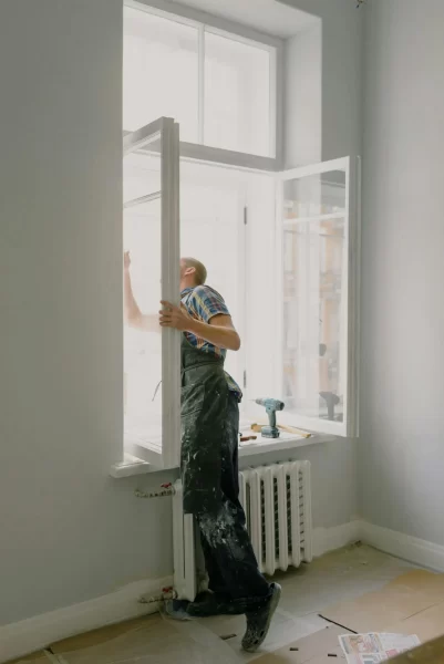 Handwerker bei der Fensterfolien-Installation in heller Wohnung mit Werkzeug.