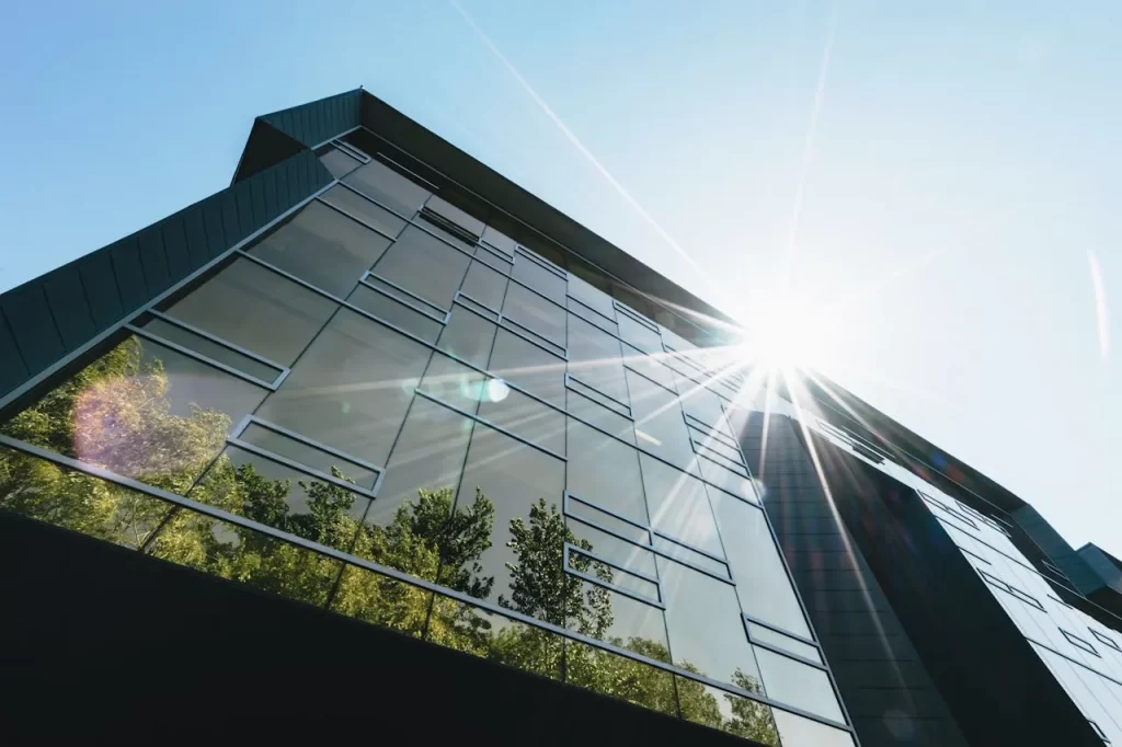 Moderne Glasfassade eines Gebäudes mit Sonnenstrahlen.