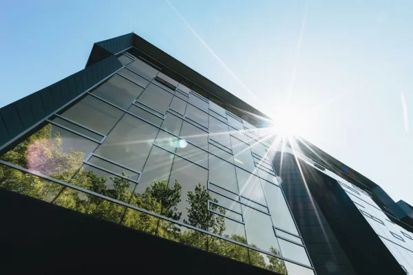 Moderne Glasfassade eines Gebäudes mit Sonnenstrahlen.