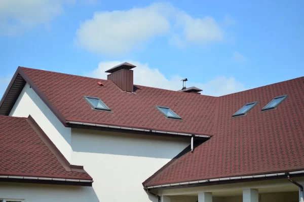 Hausdach mit mehreren Dachfenstern und einem Vordach bei Sonnenschein.