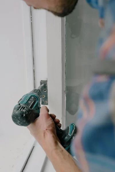 Handwerker schraubt bei Fenstermontage an Fensterrahmen