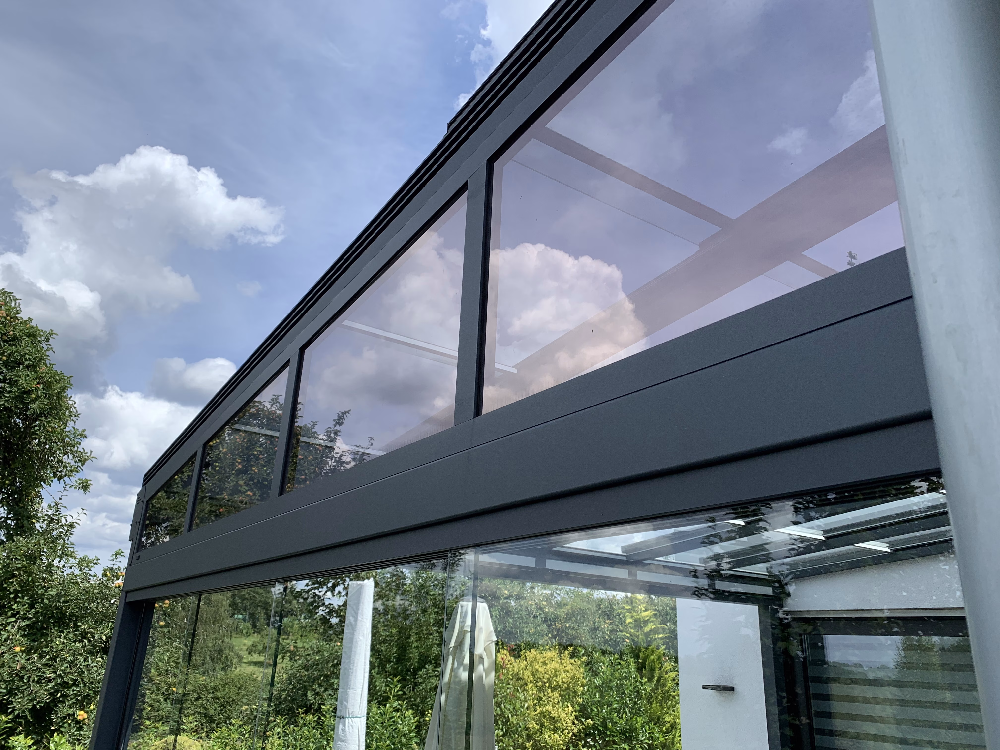 Mit der Sonnenschutzfolie bronze dunkel verspielt beklebte Fenster einer Terassenüberdachung - Außenansicht