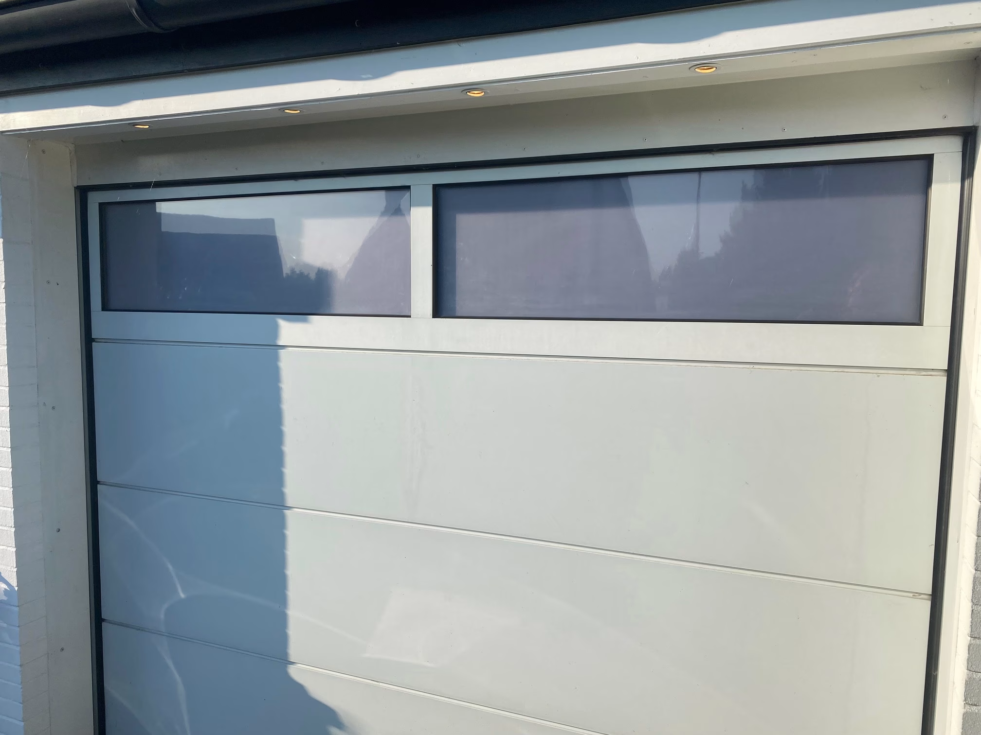Weiß matte Sichtschutzfolie auf Fenster in einem Garagentor angebracht Weiß matte Sichtschutzfolie auf Fenster in einem Garagentor angebracht