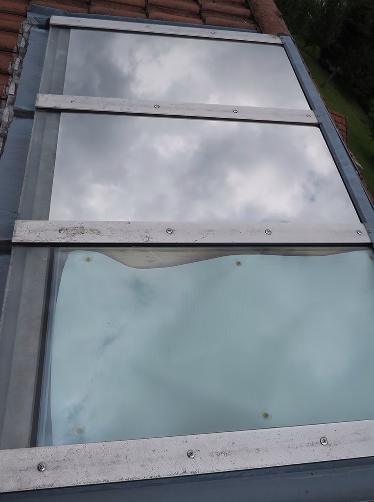 An zwei von drei Oberlichtern montierte Sonnenschutzfolie siber dunkel verspiegelt