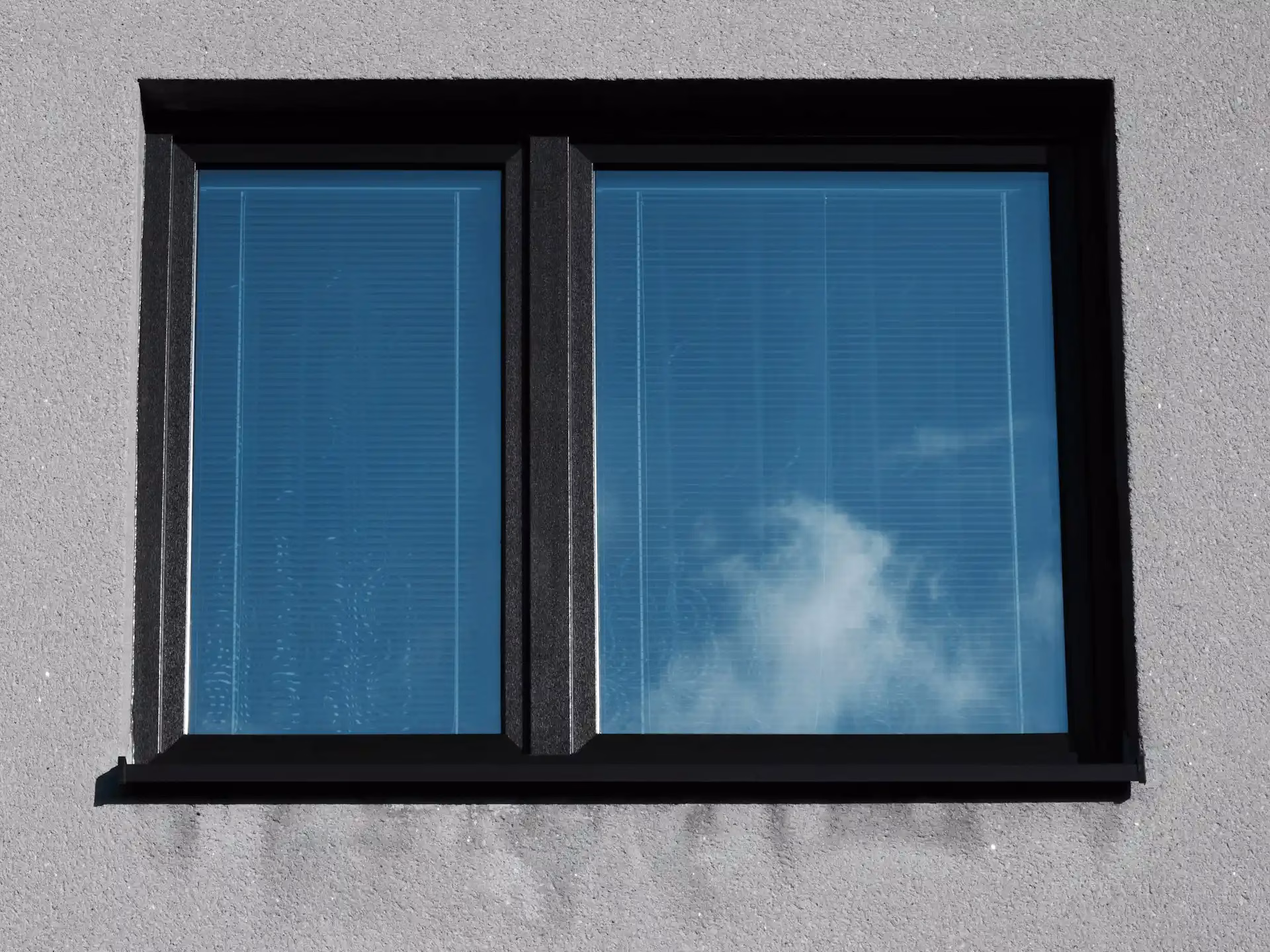 Fenster mit Spiegelung von blauem Himmel und Wolken in moderner Fassade