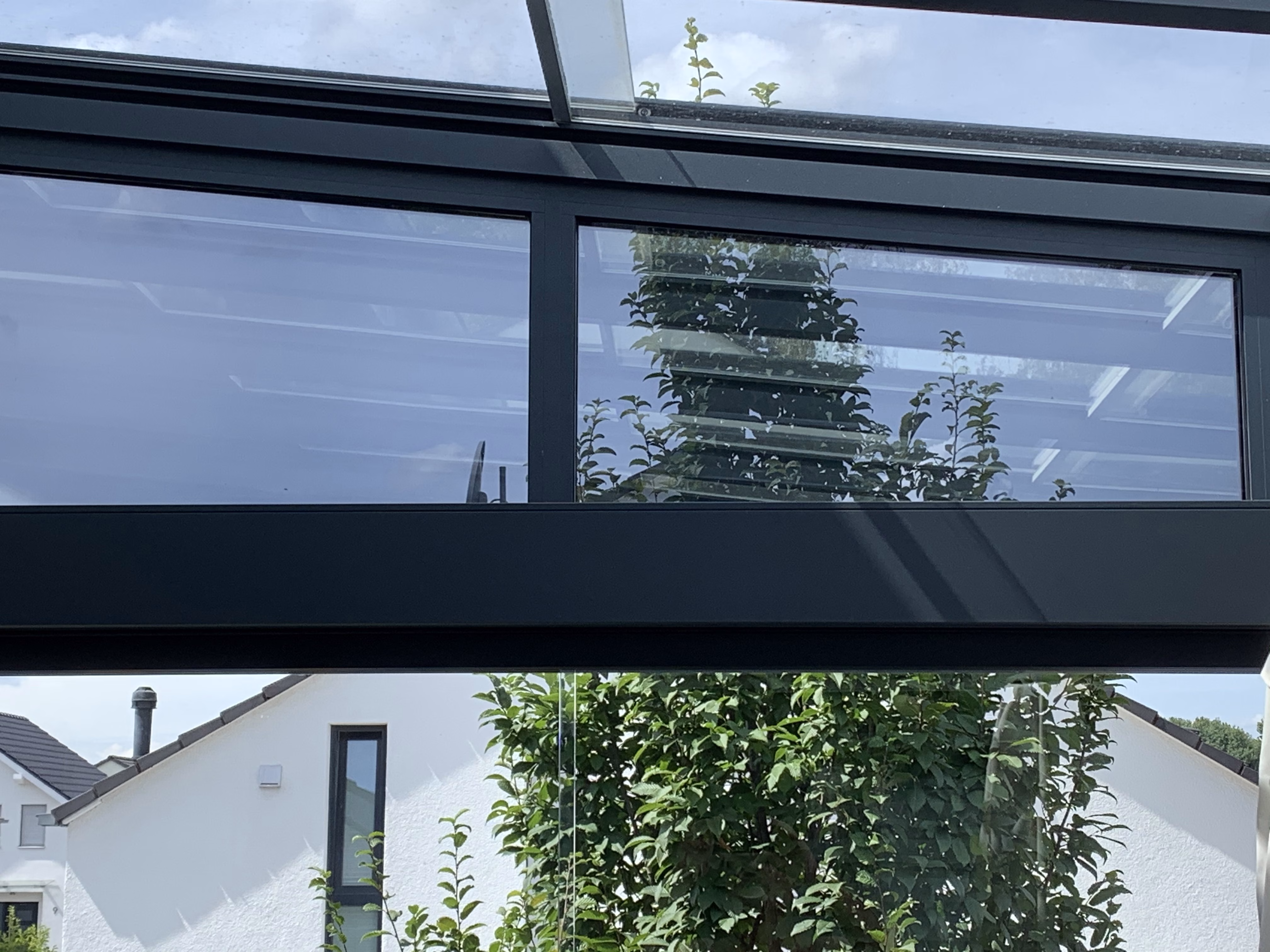 Mit der Sonnenschutzfolie bronze dunkel verspielt beklebte Fenster einer Terassenüberdachung - Innenansicht