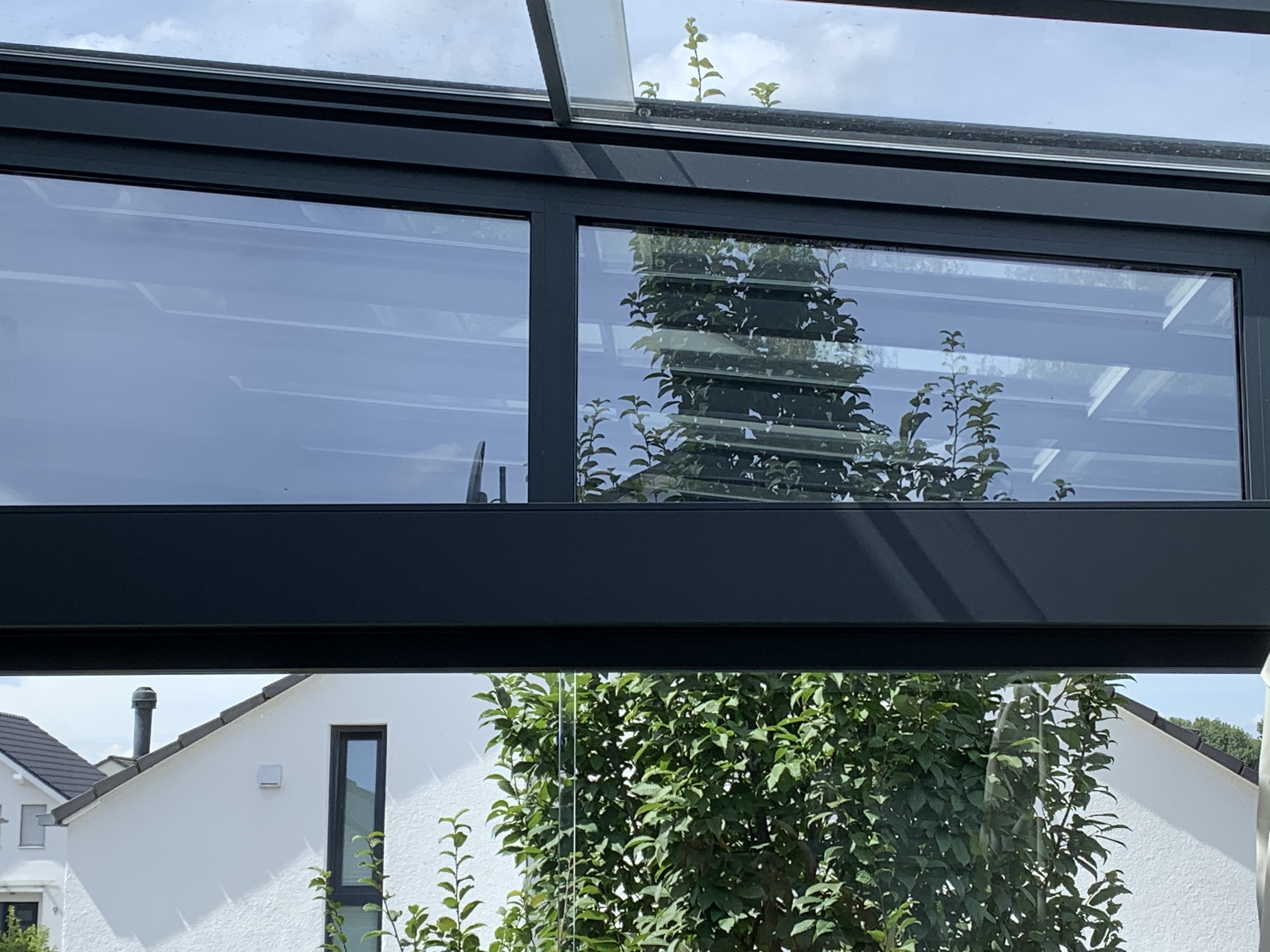 Mit der Sonnenschutzfolie bronze dunkel verspielt beklebte Fenster einer Terassenüberdachung - Innenansicht