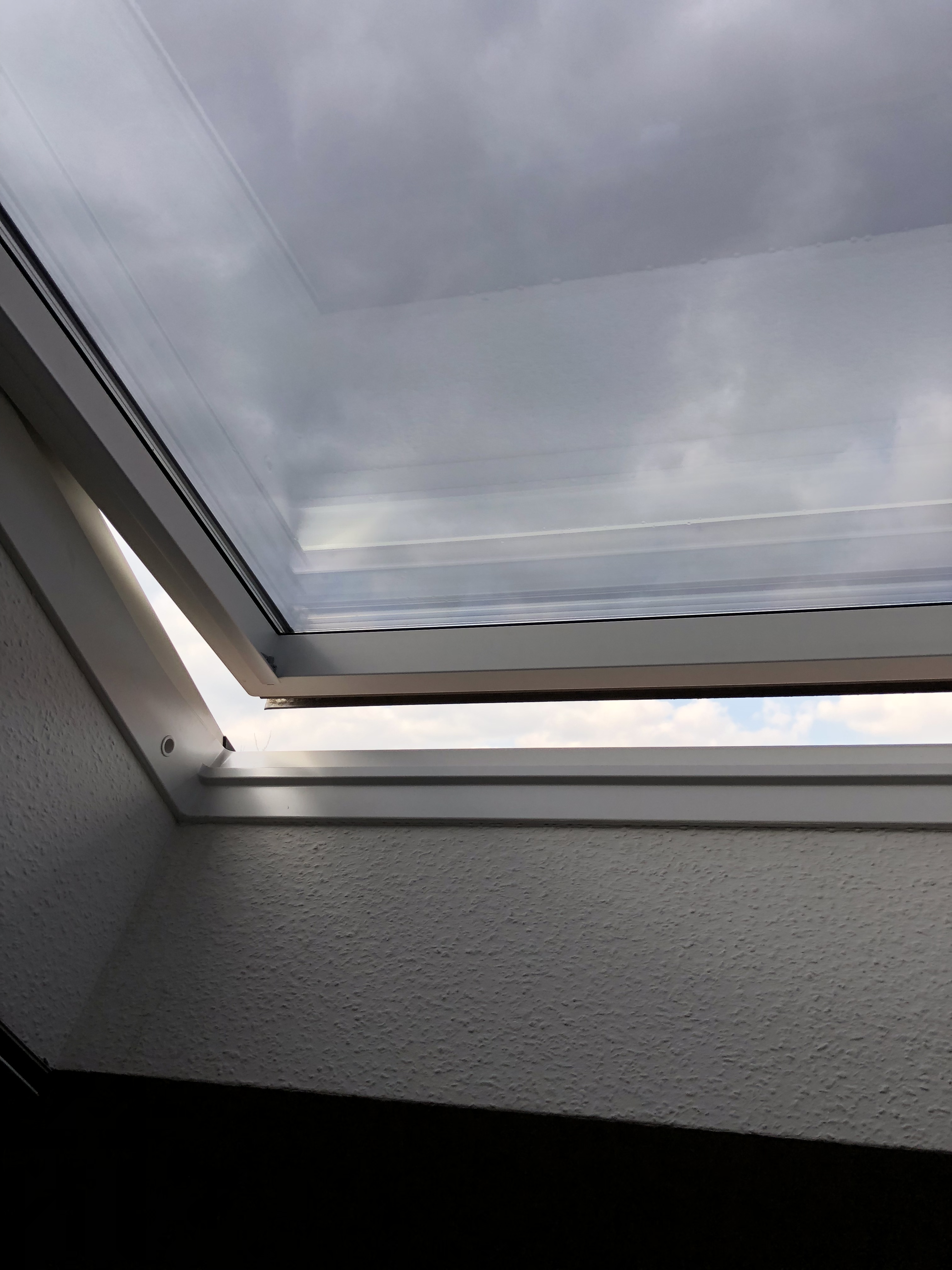 Bronzene dunkel verspiegelte Sonnenschutzfolie an einem leicht geöffnetem Dachfenster im Schlafzimmer