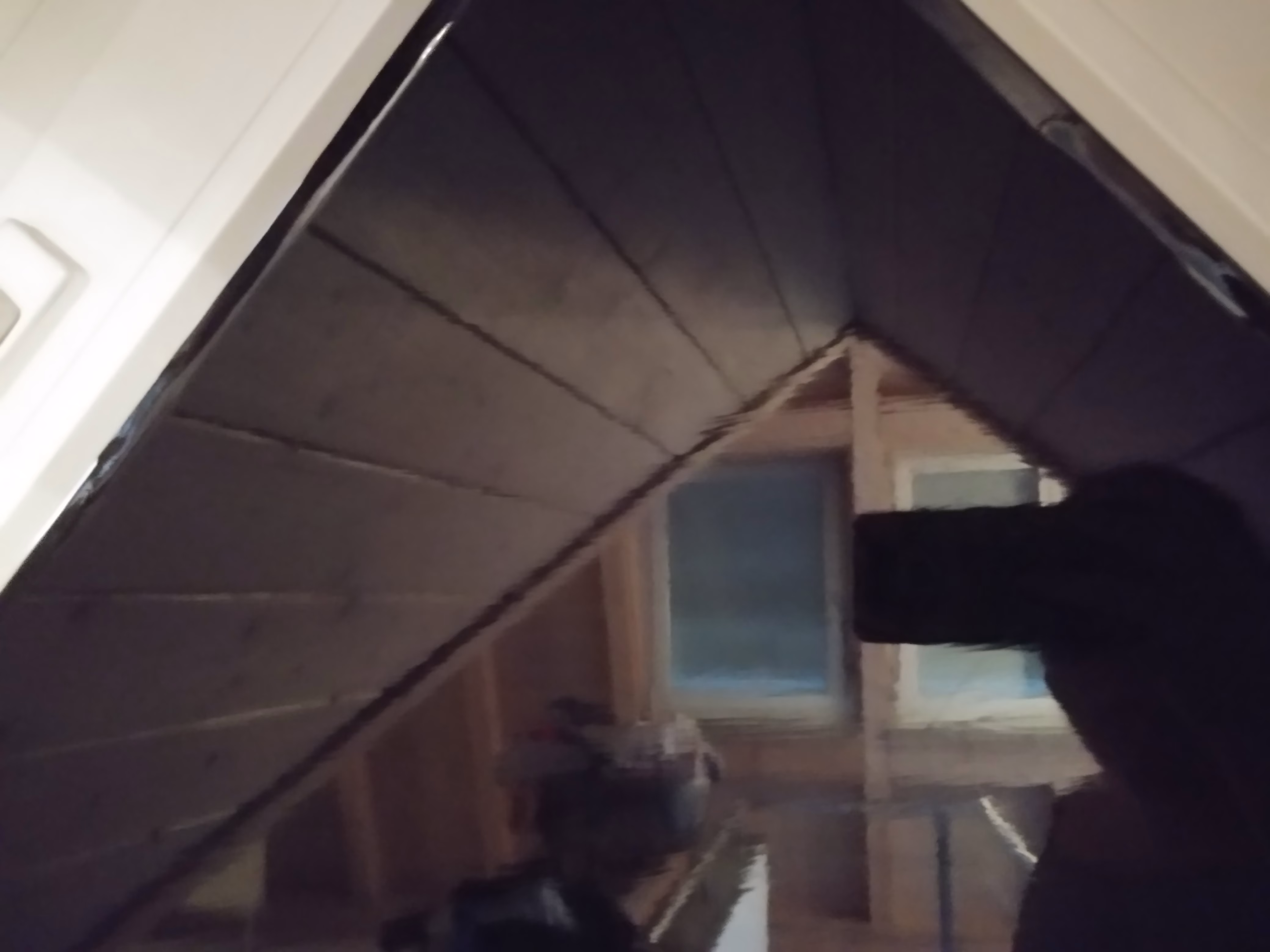 Schwarze Verdunkelungsfolie als lichtundurchlässiger Sichtschutz an einem dreieckigen Dachbodenfenster