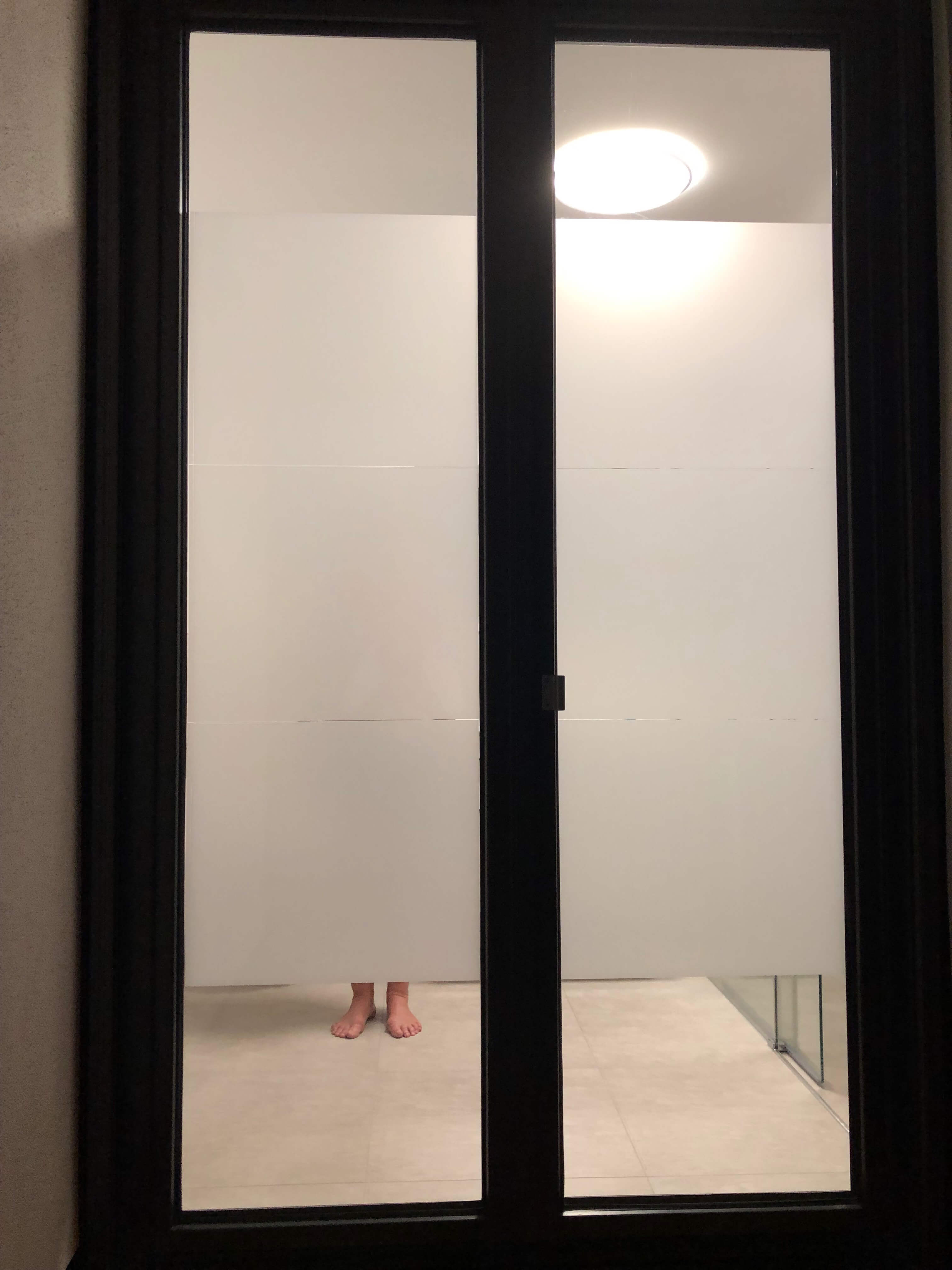 Milchglasfolie als individueller Sichtschutz auf einer Fenstertür im Badezimmer bei Nacht.