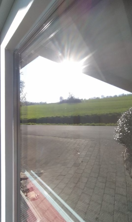 Detailansicht der Sonnenschutzfolie silber hell verspiegelt auf einem Fenster