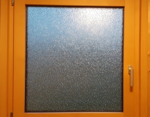 Kleberlose Sichtschutzfolie im Design Reiskörner auf einem Fenster mit Holzrahmen.
