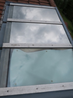 An zwei von drei Oberlichtern montierte Sonnenschutzfolie siber dunkel verspiegelt