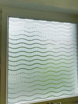 Sichtschutzfolie mit weißen Wellen auf einer Fensterscheibe