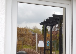 Spigelung der silber mittleren Sonnenschutzfolie an einem Fenster zur Gartenseite - Außenansicht