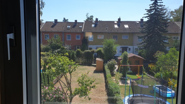 Silber hell verspiegelte Sonnenschutzfolie an einem Fenster mit Blick in den Garten