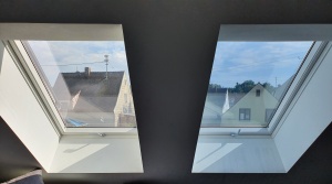 Silber mittel verspiegelte Sonnenschutzfolie angebracht auf einem Dachfenster verglichen mit folienlosem Fenster
