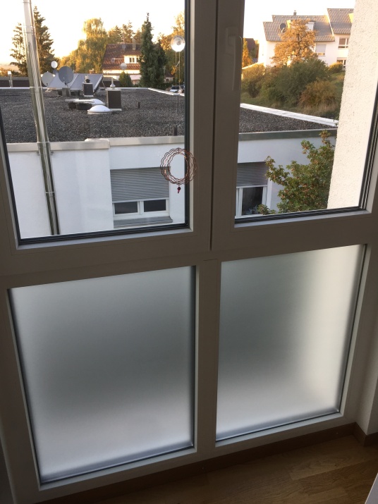 Weiß matte Adhäsionsfolie auf dem unteren Teil einer Fensterfront angebracht.
