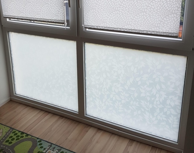 Sichtschutzfolie mit weißen Blättern auf dem unteren Teil eines Fensters geklebt