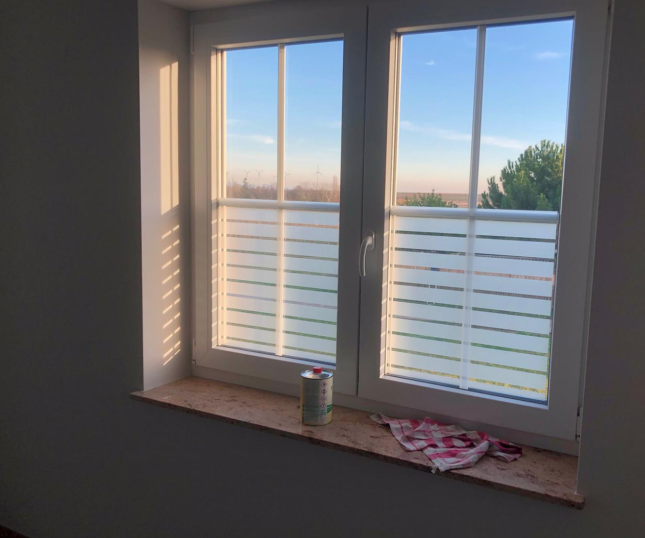Dekorfolie, horizontale Streifen weiß matt, halbhoch auf zwei Fenster montiert.