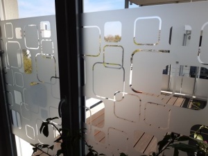 Dekorfolie transparent-weiß abgerundete Quadrate als leichter Sichtschutz von Balkonfenstern.