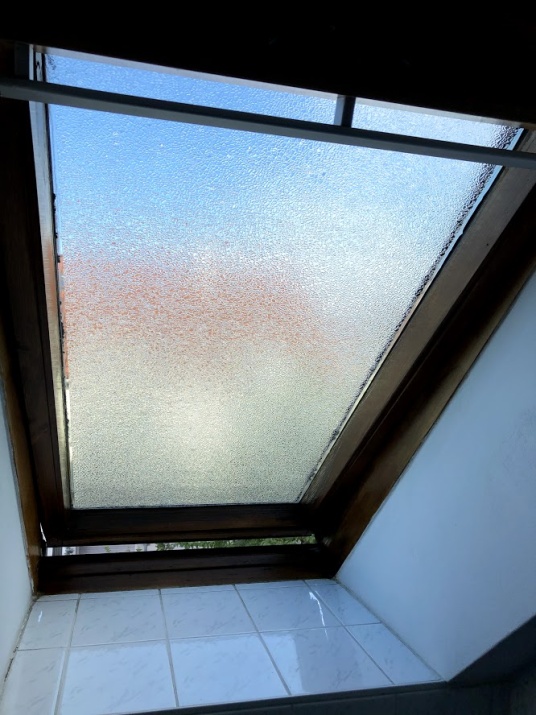 Adhäsionsfolie in Riffelglasoptik auf einem Dachfenster angebracht.